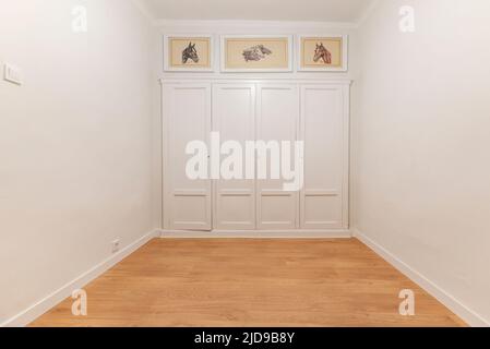 Empty room with fitted wardrobes with white wooden doors on the wall in the background Stock Photo