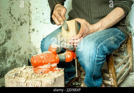 A musical instrument master filing a piece of wood used as a base for a guembri, in his workshop. Craftsmen in Marrakech, Morocco, North Africa Stock Photo