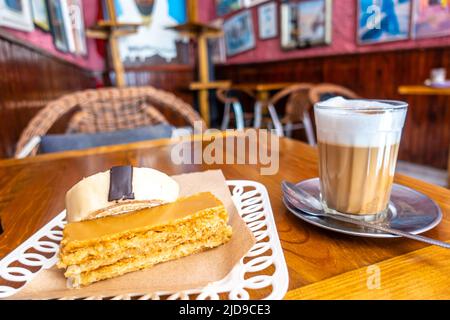 Cake and cafe latte in Patisserie Driss, fondee en 1928. Pasries, sweets, and cake historic shop and cafe in Essaouira, Morocco Stock Photo