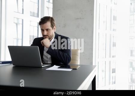 Serious focused businessman using laptop working seated at modern office Stock Photo