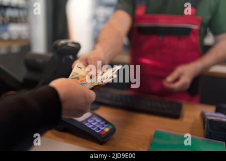 Employee taking cash payment from costumer in gas station, close-up Stock Photo