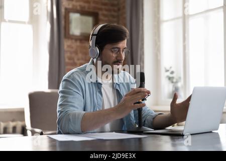 Man streamer wear headphones records podcast, makes speech into microphone Stock Photo
