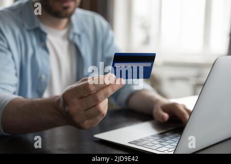 Closeup male hand holding card using laptop buying on internet Stock Photo