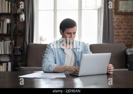 Serious office employee sit at desk working on laptop Stock Photo