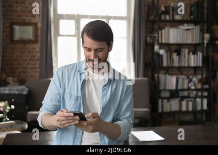 Man use smartphone standing in home office with modern smartphone Stock Photo