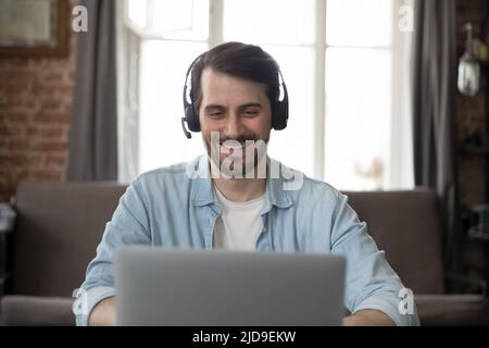 Smiling businessman wear headset use laptop having communication through videoconference Stock Photo