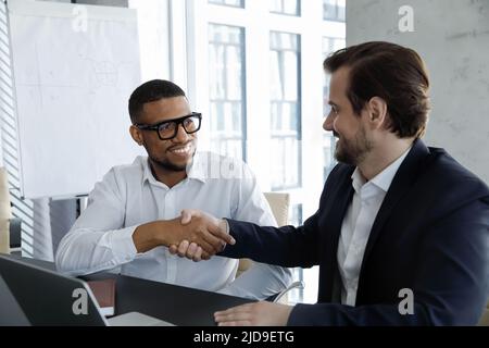 Millennial African and Caucasian businessmen handshaking accomplish meeting feel satisfied Stock Photo