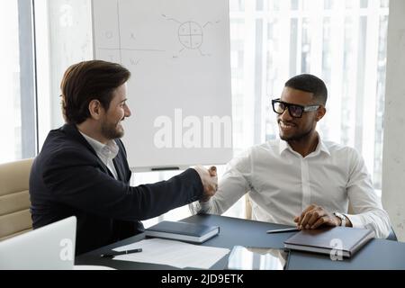 Multi ethnic business partners succeed goal, finish meeting with handshake Stock Photo
