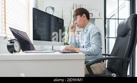 Software development concept, Male programmer looking data on laptop and typing codes on keyboard. Stock Photo