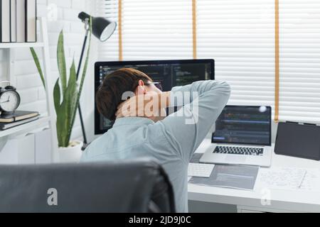 Software development concept, Male programmer suffering neck pain after working hard on computer. Stock Photo