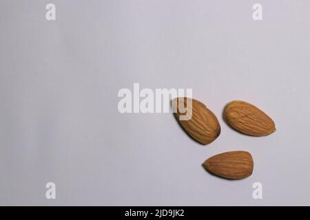 3 Almonds on a white surface, top view, text space. Stock Photo