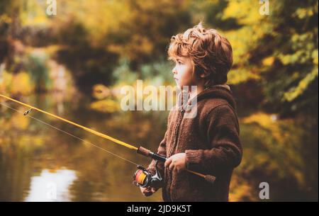 Portrait of happy little child son fishing on river with spinning reel. Happy kids autumn weekend concept. Stock Photo