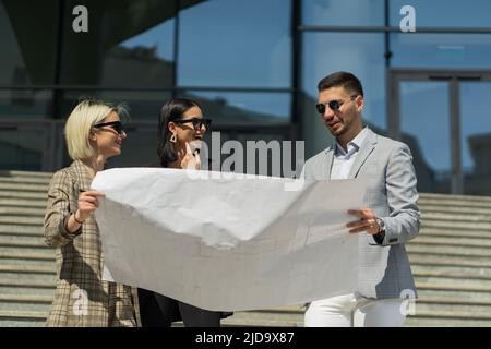 Three well suited business people with sunglasses are very satisfied with the plan Stock Photo