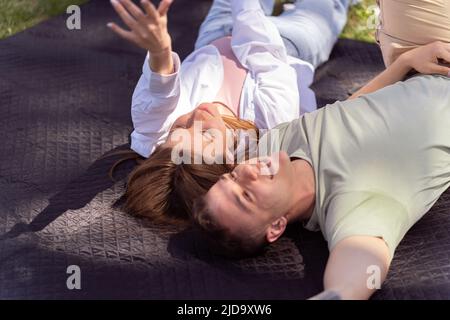 Young lovely couple or college students lying down on the grass together, listening to music, top view. Love, relationship, or relaxing casual lifesty Stock Photo