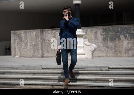 Urban businessman is going down the stairs while talking on the phone Stock Photo