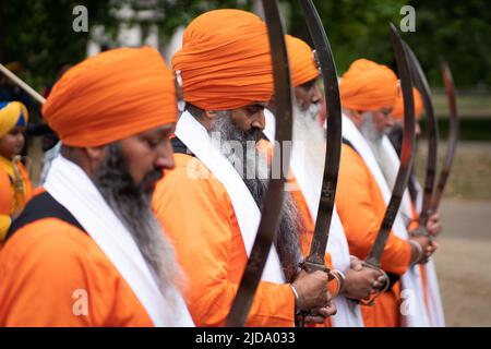 Sikh men hold their swords as they march along The Mall to Trafalgar Square, London, to take part in a rally marking the 38th anniversary of the 1984 Amritsar massacre. Picture date: Sunday June 19, 2022. Picture date: Sunday June 19, 2022. Stock Photo