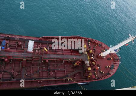 Aerial view on bow or forward part of red color bunker barge alongside of the cargo ship. Stock Photo