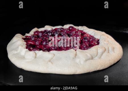 Homemade galette, open pie with cherry baking in electric oven Stock Photo