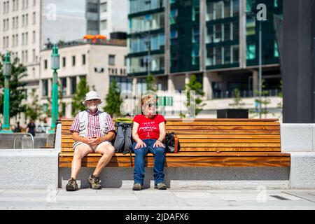 Candid photograph of man and woman couple sitting on a bench in Liverpool, England, UK on a warm sunny day Stock Photo