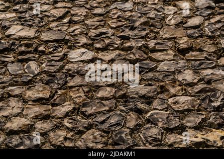 View of a big wall made of flint stones, building material in architecture used in UK. Flint is the hardest of building stones, used by the Romans for Stock Photo