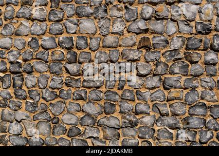 View of a big wall made of flint stones, building material in architecture used in UK. Flint is the hardest of building stones, used by the Romans for Stock Photo
