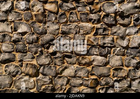 View of a big wall made of flint stones, building material in architecture used in UK. Flint is the hardest of building stones, used by the Romans for Stock Photo
