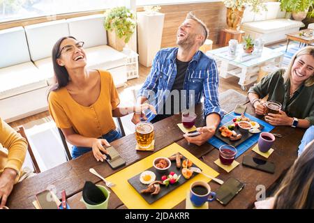 Group of friends having lunch at restaurant. Cheerful young people eating burger and enjoying at a fast food restaurant. Stock Photo