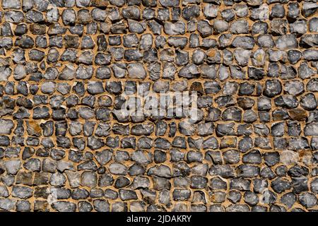 View of a big wall made of flint stones, building material in architecture used in UK. Flint is the hardest of building stones, used by the Romans for Stock Photo