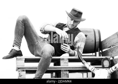 American cowboy man. Brutal western. Guy drinking whiskey. Stock Photo