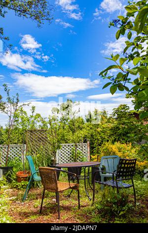 Circular metal table and empty chairs in a Saanich Peninsula garden near Victoria British Columbia Canada Stock Photo