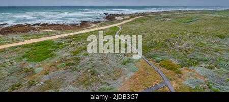 Boardwalk along the rocky shore and moorland at Cape Agulhas, the Southern Most Point of the Continent of Africa and the maritime border of the Ind... Stock Photo