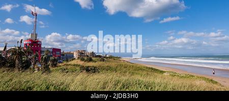 Beachfront buildings and a person standing on the shore watching the ocean surf along Dolphin Beach at Jeffrey's Bay; Eastern Cape, South Africa Stock Photo
