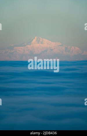 Mt Denali rises above Anchorage Alaska and the Joint Base Elmendorf Richardson Military and Air-force Base, with the foggy clouds of Cook Inlet below Stock Photo