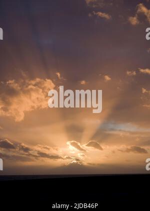 Sunset at sea with partly cloudy sky and sun rays; Brighton, East Sussex, England Stock Photo