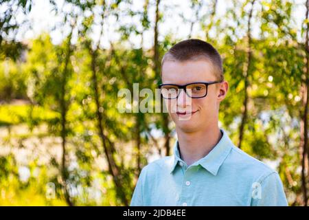 Outdoor portrait of a young man with tree foliage and water in the background; Edmonton, Alberta, Canada Stock Photo