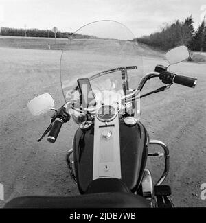 View of the handlebars, dashboard and windshield of a motorcycle parked on a roadside turnout, with a smart phone in a holder; Manitoba, Canada Stock Photo