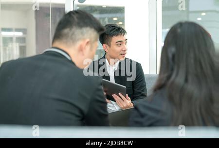 Side view view of an Asian businessman having a meeting with his colleagues. Stock Photo