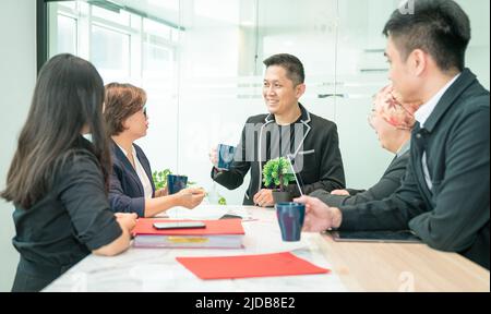 Business office colleagues discussing project over cup of coffee. Cheerful and positive vibes. Stock Photo