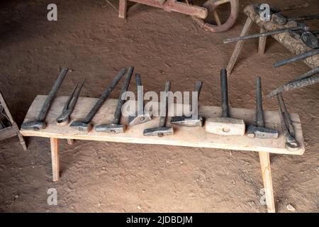 A row of hand tools on a colonial american rustic wooden bench in a Pennsylvania historical workshop. Dirt floor interior with no people and copy spac Stock Photo