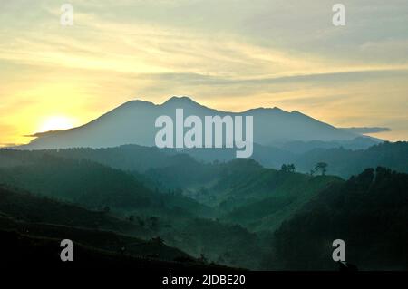 Mountain ridges covered with forest and bushes in a background of Mount Pangrango (left) and Mount Gede, which are the core zone of Mount Gede Pangrango National Park, photographed from Benda village in Cicurug, Sukabumi, West Java, Indonesia. Stock Photo