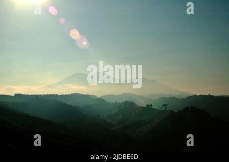 Mountain ridges covered with forest and bushes in a background of Mount Pangrango (left) and Mount Gede, which are the core zone of Mount Gede Pangrango National Park, photographed from Benda village in Cicurug, Sukabumi, West Java, Indonesia. Stock Photo