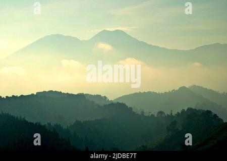 Mountain ridges covered with forest and bushes in a background of Mount Pangrango (left) and Mount Gede, which are the core zone of Mount Gede Pangrango National Park, photographed from Benda village in Cicurug, Sukabumi, West Java, Indonesia. Stock Photo