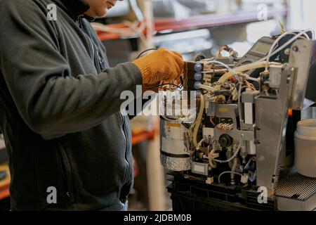 Professional worker fixing coffee machine in workshop Stock Photo