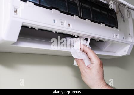cleaning a dirty and dusty air conditioning filter in the house. male removing a dusty air conditioner filter. Stock Photo