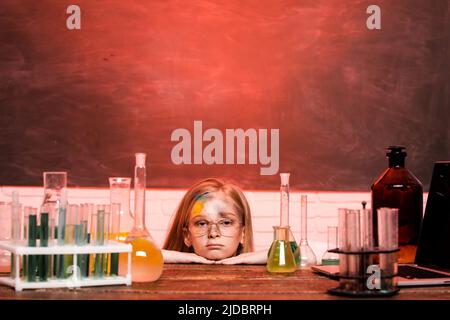 Chemical experiment. Funny schoolgirl kid with test tubes in school classroom doing experiments. Explosion in the lab. Science and education. Little Stock Photo