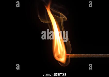 Artfully curved flame and smoke of a lit match in front of a black background Stock Photo