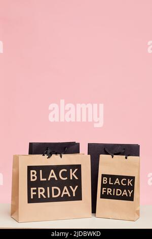 Background image of shopping paper bags with Black Friday lettering against pink wall in womens store Stock Photo