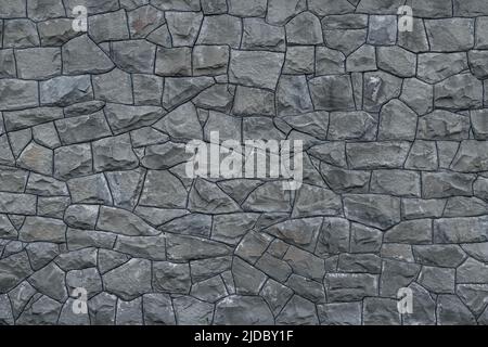 Gray dirty stone wall. Texture of grey granite. Dark rough rocks background. Weathered dark gray grunge building's facade. Stone surface. Mosaic patte Stock Photo