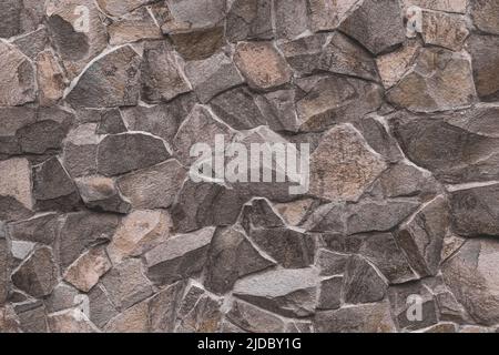 Abstract pattern of brown stone texture. Brick wall background. Rough granite surface. Cracked rock. Decorative tile on facade of building. Stock Photo