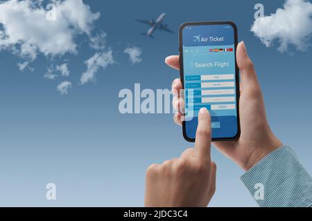 User holding a smartphone and booking cheap flights online, sky in the background, POV shot Stock Photo